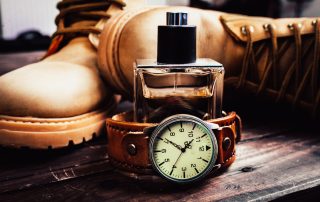 best father's day cologne bottle sitting inside a watch wristband next to a pair of work boots