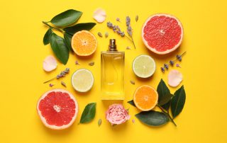 grapefruit perfume surrounded by fresh fruit on yellow background