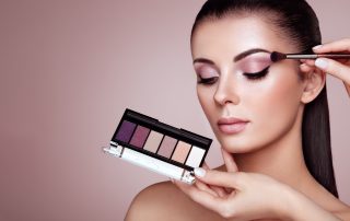makeup artist applying eyeshadow to a young woman