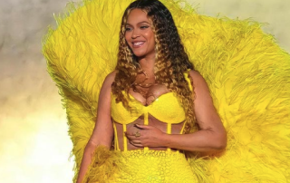 Beyonce standing in a yellow dress with feathers
