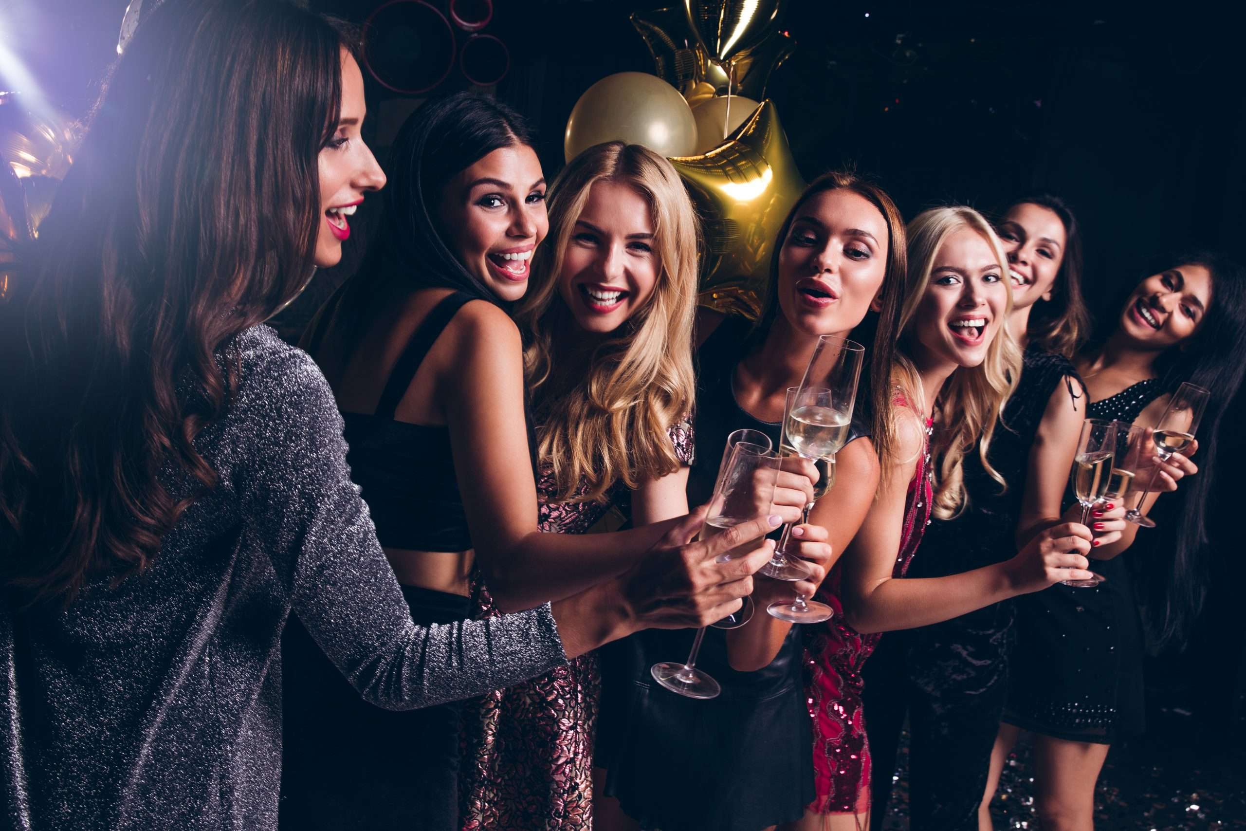 group of young women celebrating 21st birthday, smiling, and drinking wine