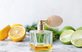 bottle of citrus perfume surrounded by lemons and limes on a light background