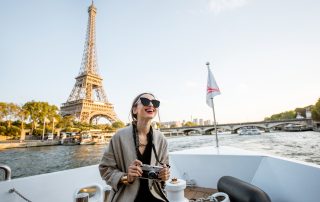 Young woman enjoying beautiful landscape view on the riverside with Eiffel tower from the boat during the sunset in Paris