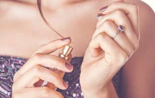 Young woman applying perfume on her wrist