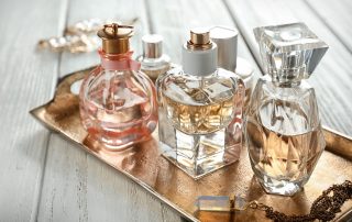 vintage tray holding a small collection of perfume bottles sitting on top of a white wooden table