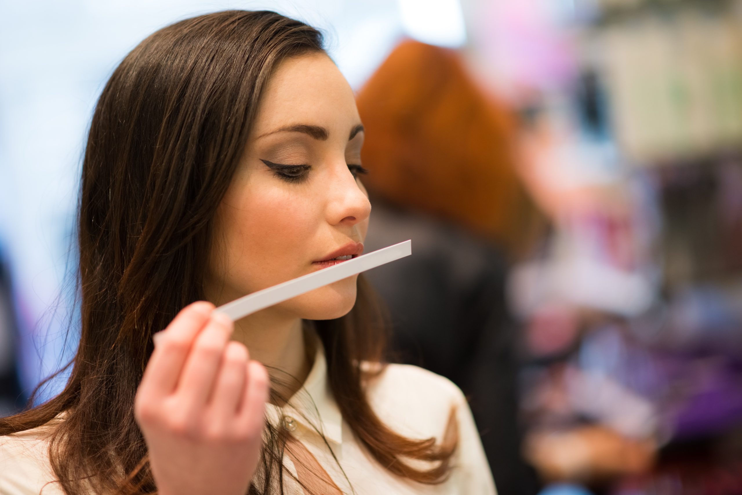 brunette woman smelling a perfume tester in a shop