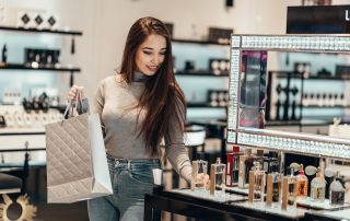 Happy beautiful Asian girl smiling young girl buys perfume cosmetics in the store