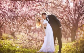 bride and groom standing in spring garden surrounded by trees