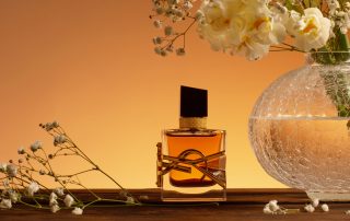 Yves Saint Laurent Libre perfume sitting on a table next to a clear vase of white flowers