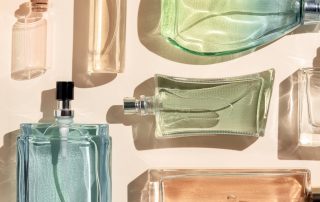 perfume bottles. a lot of transparent multicolored glass bottles of cosmetics, on a beige background. art composition flat lay panoramic.