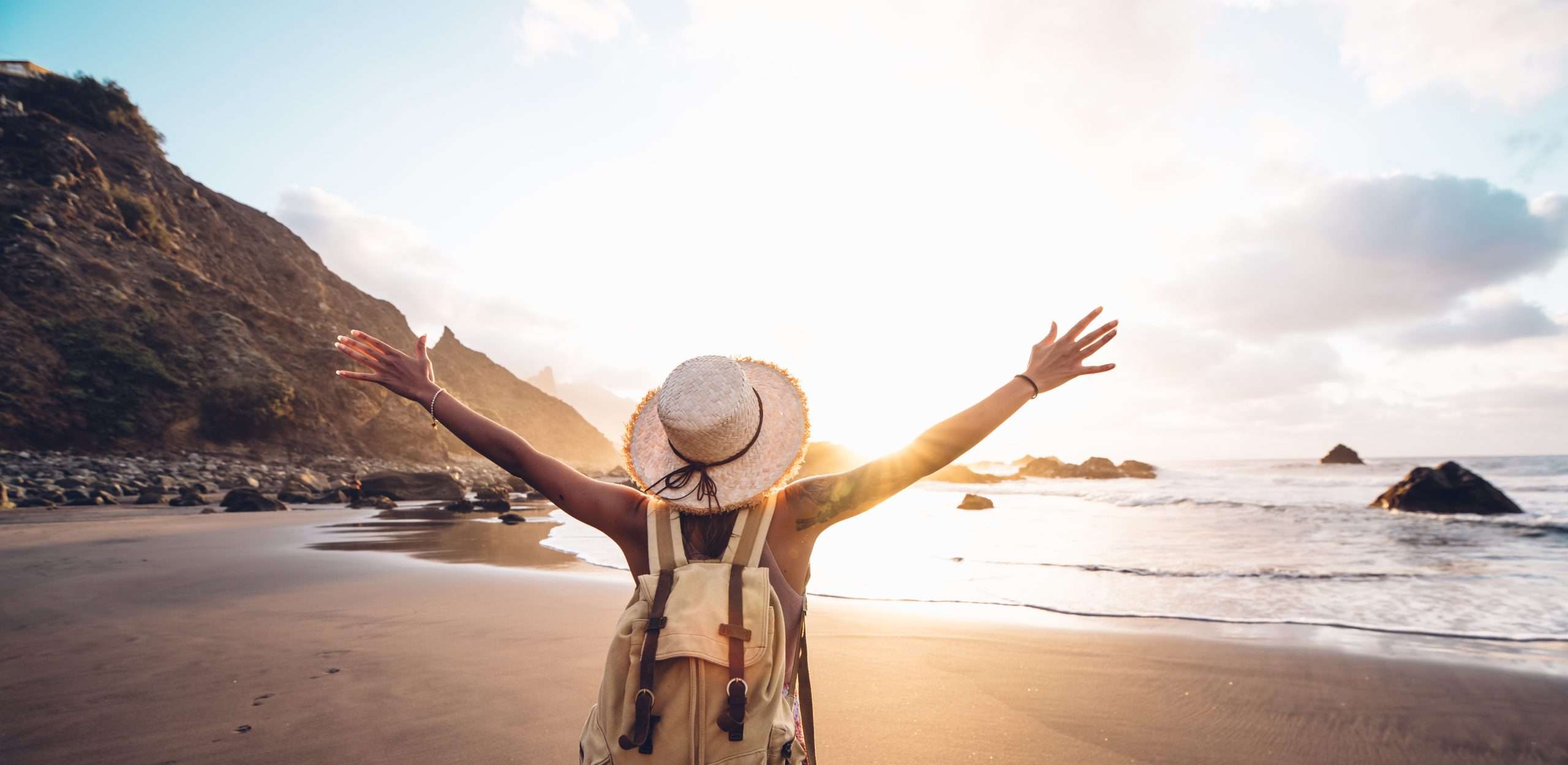 Happy woman with arms up enjoy freedom at the beach at sunset. Wellness, success, freedom and travel concept - perfumes for every type of vacation