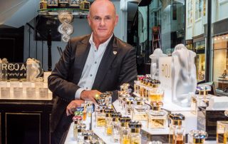 Roja Dove standing behind a display of Roja Parfums
