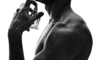 Handsome man with bottle of perfume on white background