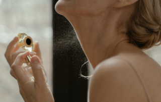 Woman spraying perfume on her neck - closeup