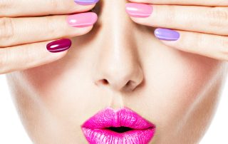 Close-up face of a woman with multicolor nails pink lips